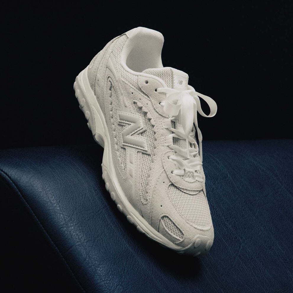 A grey shoe sitting on a dark blue studio backdrop.